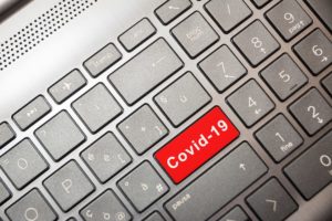 Bright red key that says "Covid-19" in white letters in a gray keyboard viewed from above. 
