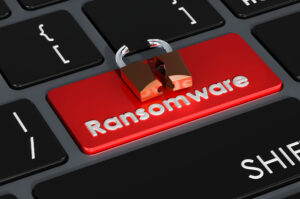 A close up of a black keyboard with a bright red key that says "Ransomware" with a broken padlock on top of it.