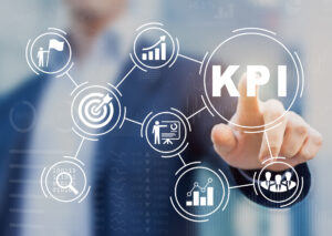 A man in the background points to a circle that says KPI in the foreground, next to other circles with bar graphs, a target and other analytics symbols.