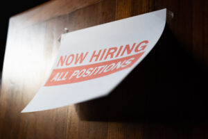 A paper sign that says in red, "Now hiring all positions."