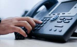 Close up of a person's hand dialing on a deskphone in an office.