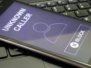 Close up of a smartphone lying on a keyboard with an incoming call from "unknown caller."