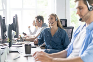 A row of four call center agents at work in a sunny room.