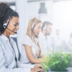 A row of call center workers in a sunny room.