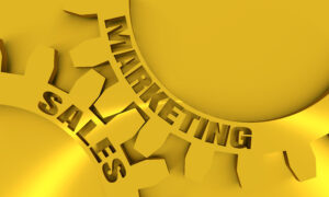 A close up of two golden gears labeled sales and marketing, representing sales and marketing alignment.