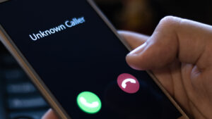 Close up of a person holding their smartphone with a call coming in from "Unknown Caller." 