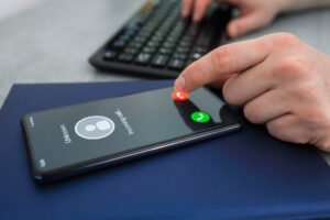 Close up of a person at their keyboard receiving an incoming call from "Unknown" and hitting the reject call option. 