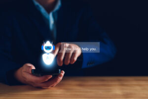 A person uses their smartphone with a glowing blue robot symbol floating over it and saying "Hi, how can I help you?" symbolizing contact center AI solutions.