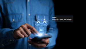Close up of a person using a smartphone with an image of a robot labeled "AI" hovering over the screen. The AI has a speech bubble that reads, "Hello! How can I assist you?"