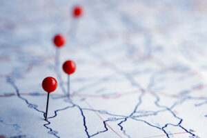 Close up of four red-topped push pins on a road map. 