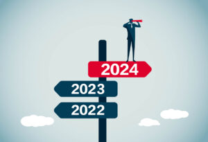 An illustration of a sign post with arrows for 2022 and 2023 pointing left. A small figure wearing a suit and looking through a telescope stands atop a third sign post at the top of the pole. The top sign post reads 2024, points to the right, and is red.
